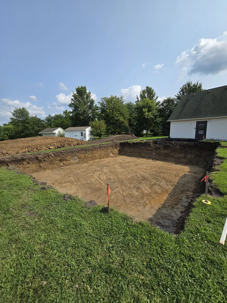 A squared-off basement excavation dug tight beside a house